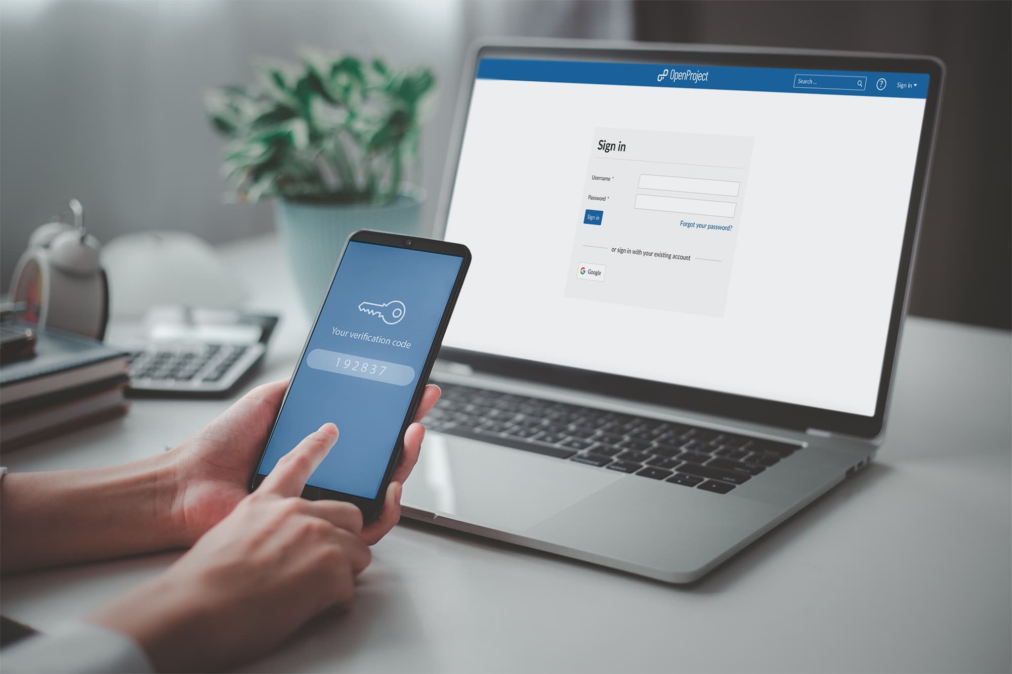 laptop screen with OpenProject login page and mobile phone with 2 factor code