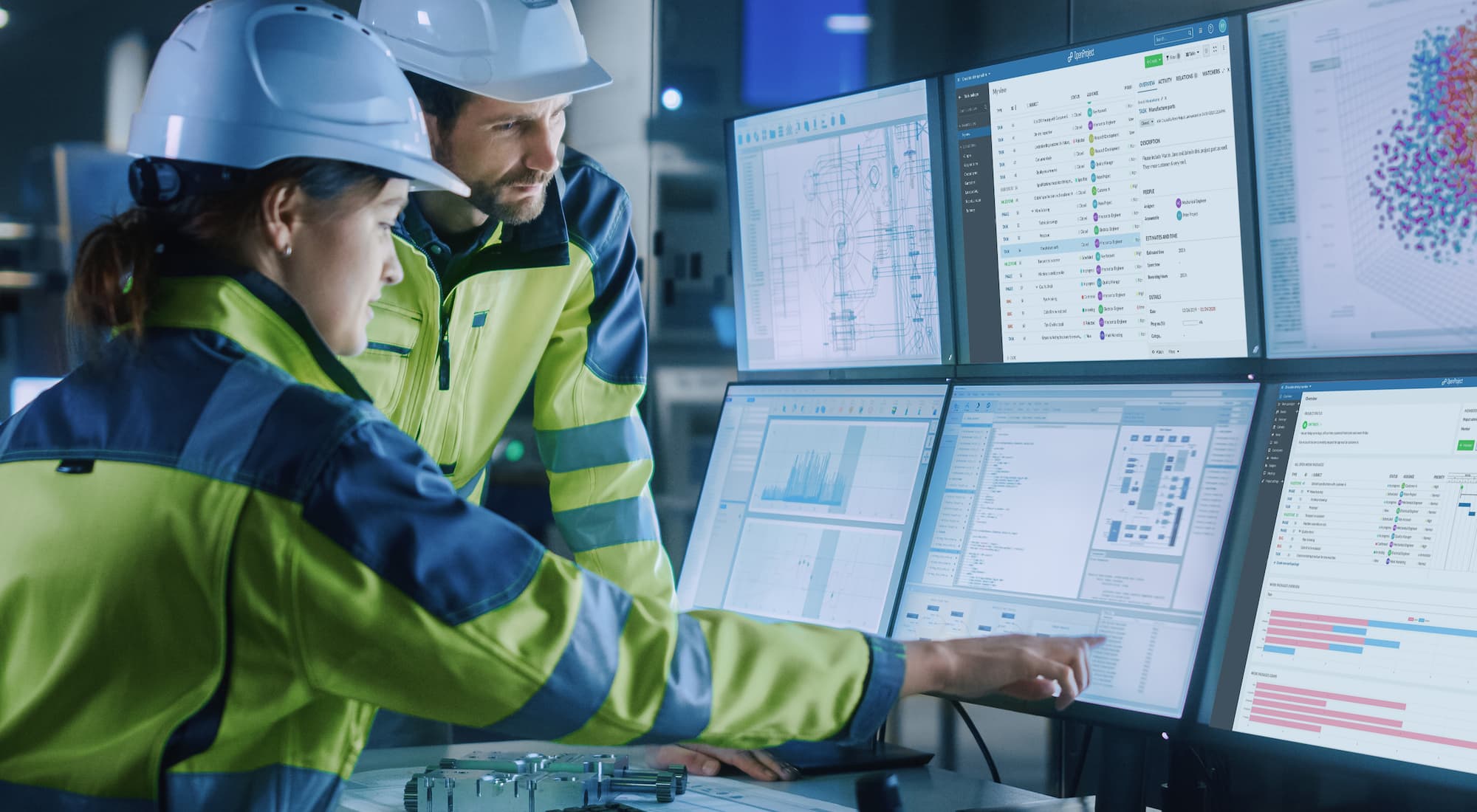 People in construction outfits pointing to screens which display the OpenProject software